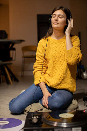girl sitting on floor enjoys to music with headphones and analog turntableの写真素材