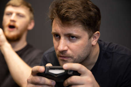 two handsome guys play passionately video game holding console joystick in handsの写真素材