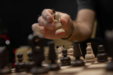 Man taking next step on chess game. Human hand moving wooden white chess kingの写真素材