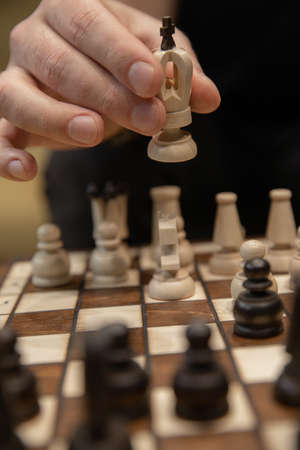 Man taking next step on chess game. Human hand moving wooden white chess kingの写真素材