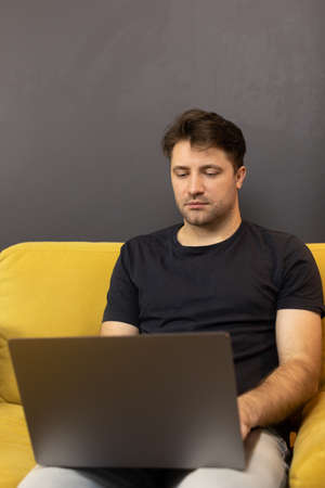 web designer working from home distantly sitting on sofa with laptop computerの写真素材