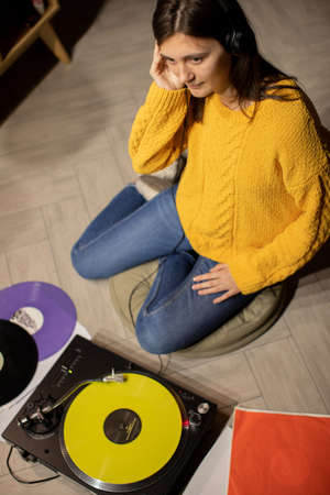girl sitting on floor enjoys to music with headphones and analog turntableの写真素材