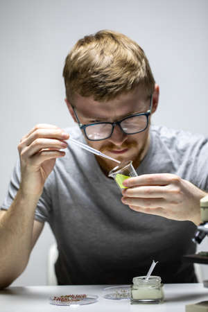 young bearded biologist Geneticist in glasses drops green reagent on plant leafの写真素材