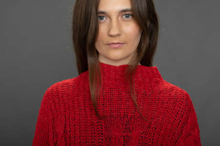 Close-up young pretty woman looks at camera on grey background, power lookの写真素材