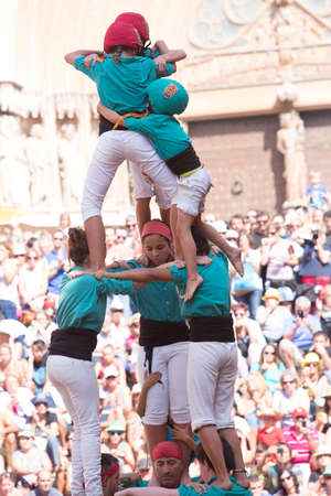 Tarragona, Spain, September 19, 2019 - Children complete erection of human castells tower by climbing to top. Dangerous tense moment close-up.のeditorial素材