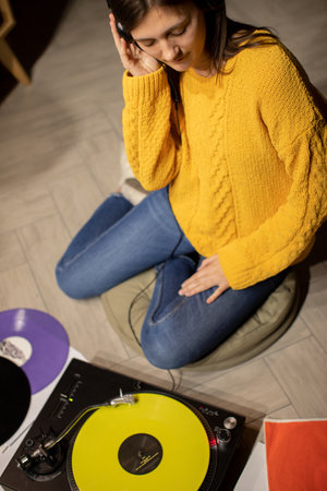 girl sitting on floor enjoys to music with headphones and analog turntableの写真素材