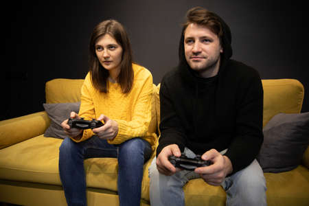 couple playing video games on couch. Evening lifestyle family entertainmentの写真素材
