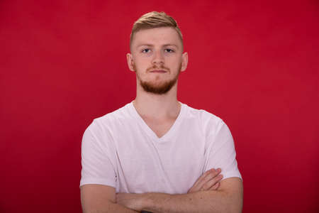 Handsome athletic man seriously looks at camera, red background, gym, copy spaceの写真素材