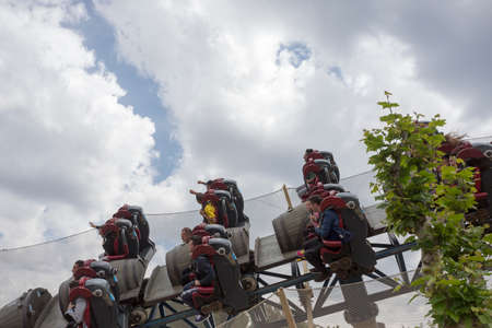 Salou, Spain, May 1, 2020 - Furious Baco riders over Port Aventura amusement park against cloudy sky. Adrenalin attraction concept. Hyper-speed loop Exciting funのeditorial素材
