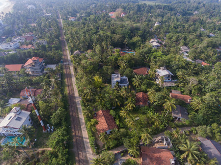 Hikkaduwa, Sri Lanka, 1.12.2020 - Amazing aerial view of railroads, cell tower, cottages surrounded by tropical greenery and palm treesの写真素材