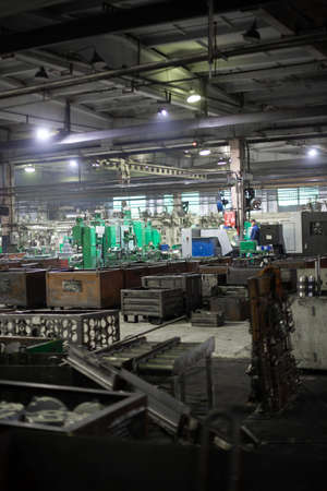 metal processing workshop full of containers with workpieces. Obsolete industrial equipment and processes, unautomated dirty production. Environmental pollution, harmful emissionsの写真素材