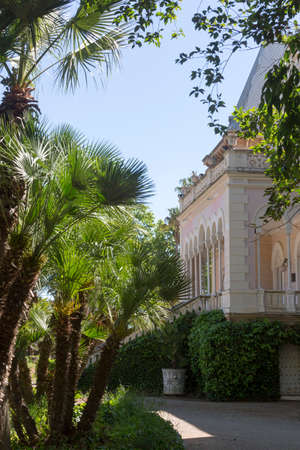 Cambrils, Spain, May 1, 2020 - Castle in Botanical Garden Park Sama in midst of palm trees. Beautiful Park Landscape. Potted and green creeping plants on wall of mansionのeditorial素材