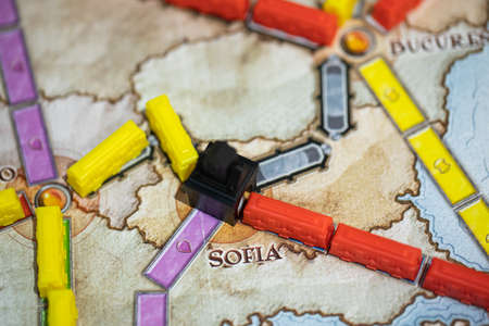 London, GB 11.02.2021 - Ticket to Ride elements standing on Europe map. Plastic colorful train cars, stations connecting Sofia city. Close-up. Board game for home entertainment, family leisure timeのeditorial素材