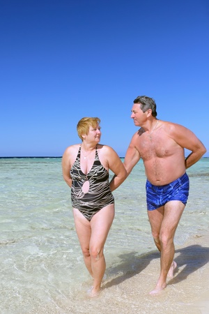 Mature couple walking on the beach in tropical resort.の写真素材