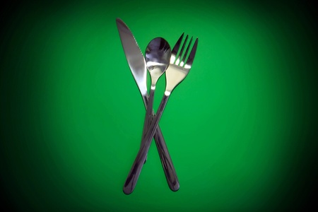 Table serving-knife,plate,fork on  green colour background.