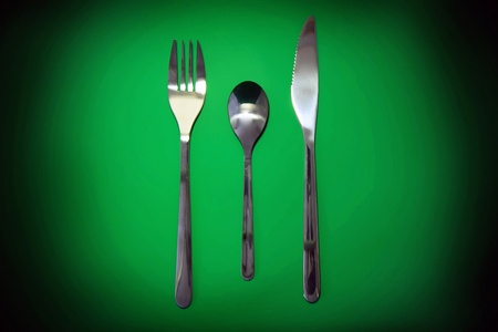 Table serving-knife,plate,fork on  green colour background.の写真素材