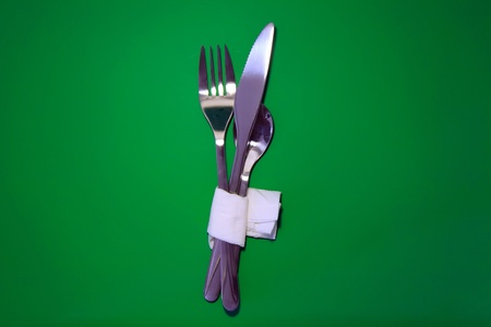 Table serving-knife,plate,fork on  green colour background.の写真素材
