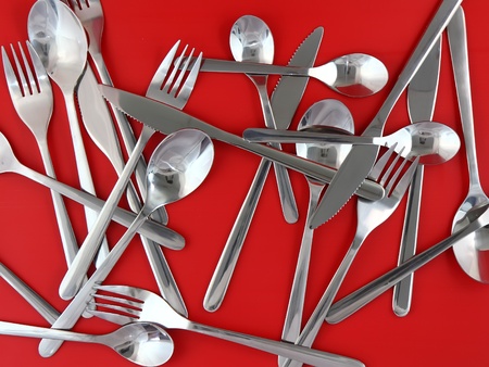 Table serving-knife,plate,fork and   on  red background. Texture