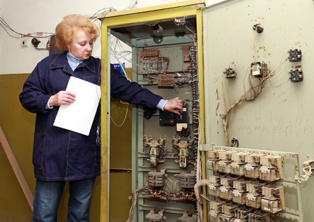 Operator woman-engineer in machine room (elevator) check the mechanical relay and cabinet.の写真素材