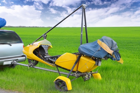 Motorized hang glider over green grass, ready to fly.