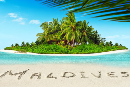 Whole tropical island within atoll in tropical Ocean. Uninhabited and wild subtropical isle with palm trees. Inscription "Maldives" in the sand on a tropical island,  Maldives.の写真素材