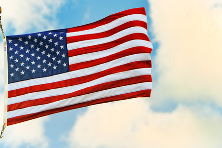 Star-striped American flag flutters proudly against the blue sky. USA.