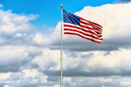 Star-striped American flag flutters proudly against the blue sky. USA.