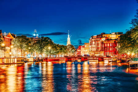 AMSTERDAM, NETHERLANDS- SEPTEMBER 16, 2015: Famous Amstel river and night view of beautiful Amsterdam city. Boats, cars on street. Netherlandsのeditorial素材