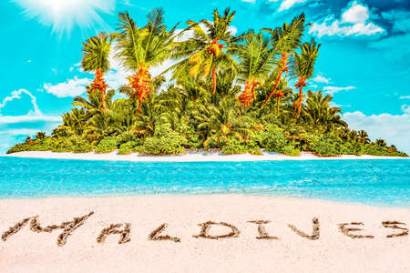 Whole tropical island within atoll in tropical Ocean. Uninhabited and wild subtropical isle with palm trees. Inscription "Maldives" in the sand on a tropical island,  Maldives.の写真素材