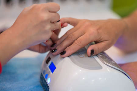 Nail care and manicure. Closeup of beautiful woman hands getting manicure in spa salon. Female manicurist cleaning cuticle with professional manicure pusher tool. Cosmetic procedure.の写真素材