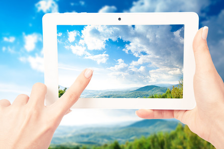 tablet computer in hand on the forest backgroundの写真素材