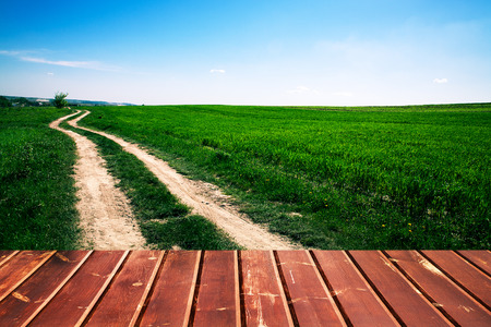 Wood floor over yellow wheat field under nice sunset cloud sky backgroundの写真素材