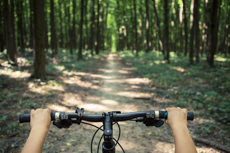 Mountain biking down hill descending fast on bicycle. View from bikers eyes.の写真素材