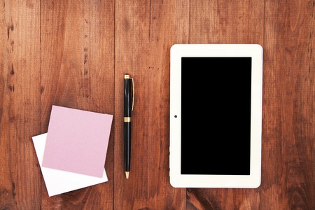 Empty white porcelain cup of coffee and pen with notes on brown wooden backgroundの写真素材