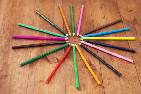 multicolored pencils on the brown wooden table backgroundの写真素材