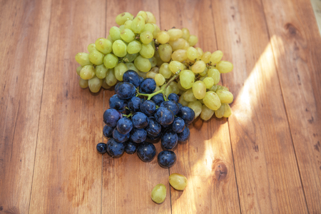 Green and purple round grapes on old wooden table, selective focusの写真素材