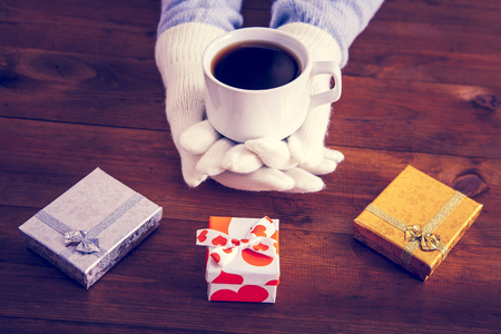coffee in hands with gifts on a wooden backgroundの写真素材