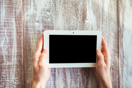 a mobile telephone in hands for a girl is isolated on a wooden background
