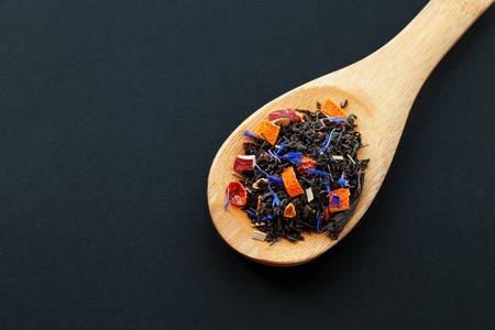 assortment of dry tea in wooden spoon, on black backgroundの写真素材