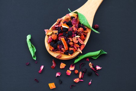 assortment of dry tea in wooden spoon, on black backgroundの写真素材