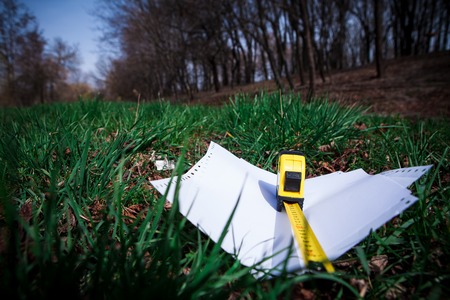 Papers and tape-measure with pencil on green grass in the parkの写真素材
