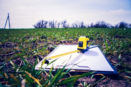 Papers and tape-measure with pencil on green grass in the parkの写真素材