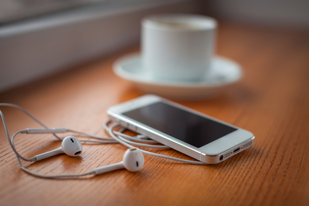 Smartphone, headphones and coffee cup on wooden tableの写真素材