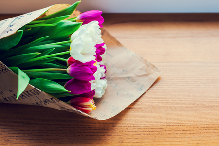the bouquet of tulips is wrapped in a paper isolated on a wood backgroundの写真素材