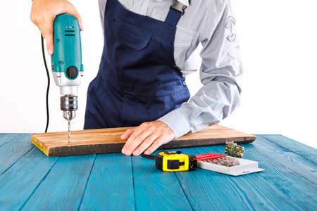 Handyman in blue uniform works with electricity automatic screwdriver. House renovation conception.