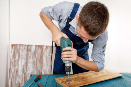 Handyman in blue uniform works with electricity automatic screwdriver. House renovation conception.の写真素材