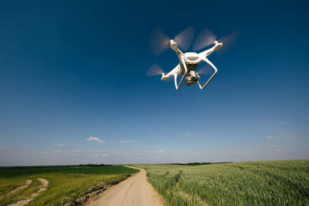 Drone quadcopter flying over green field in summer.の写真素材