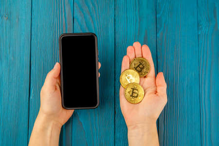 bitcoin, woman with mobile phone and golden coin and bitcoin in hands.の写真素材