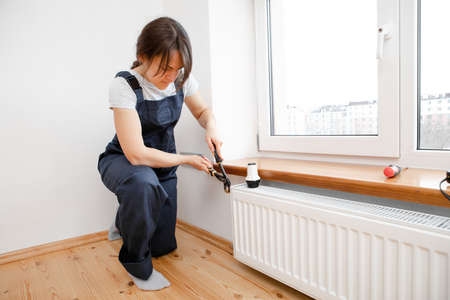 Repair heating radiator close-up. woman repairing radiator with wrench. Removing air from the radiatorの写真素材