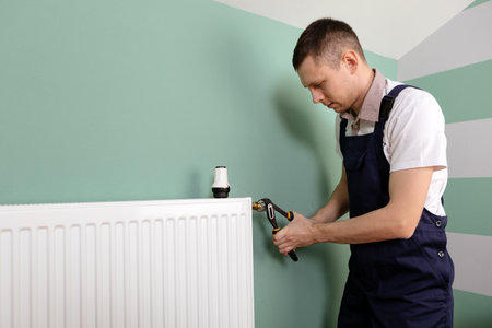 Repair heating radiator close-up. man repairing radiator with wrench. Removing air from the radiatorの写真素材